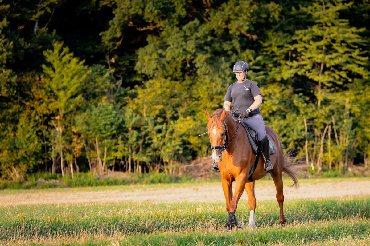 Physiotherapeutin Kerstin reitet auf einem Pferd fürs Bewegungstraining